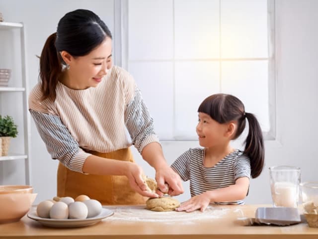 きれいなキッチンで楽しくクッキーの生地をこねる親子