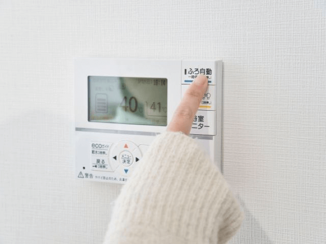 エコキュート給湯器の操作パネルで給湯温度を調整している様子。
