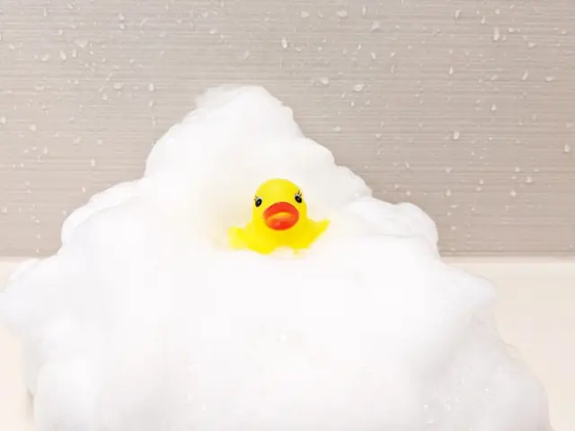 浴槽の泡の中に浮かぶ黄色いあひるのおもちゃの写真