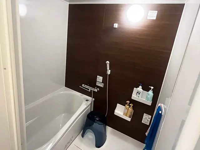 沖縄のお風呂リフォーム後のユニットバス。ダーク木目パネルが映える落ち着いた浴室空間。