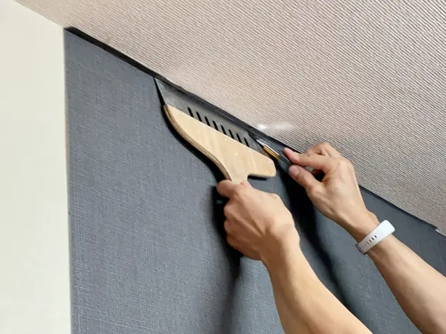 築20年の住宅で職人が壁紙クロスを丁寧に張り替えている施工風景。壁紙リフォームで失敗しない選び方を提案する地域密着のニッシンあっとリフォーム。