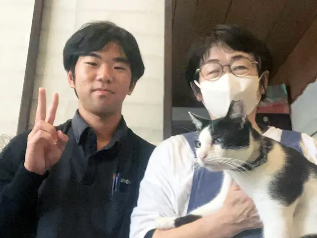 南城市での水回りリフォーム完了後、担当者の稲嶺と笑顔で記念撮影をするお客様（H.T様）と愛猫。地域密着の温かいサポートを象徴する一枚。